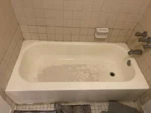 Damaged bathtub with peeling surface before refinishing in Miami