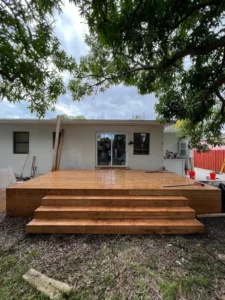 Completed wooden deck installation with steps in backyard area - Miami home improvement