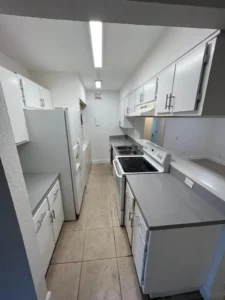 Renovated kitchen with white cabinets, gray countertops, and a clean modern finish in a Miami home