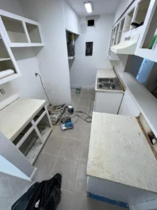 Old kitchen cabinets and countertops being prepped for renovation in a narrow galley-style layout in Miami